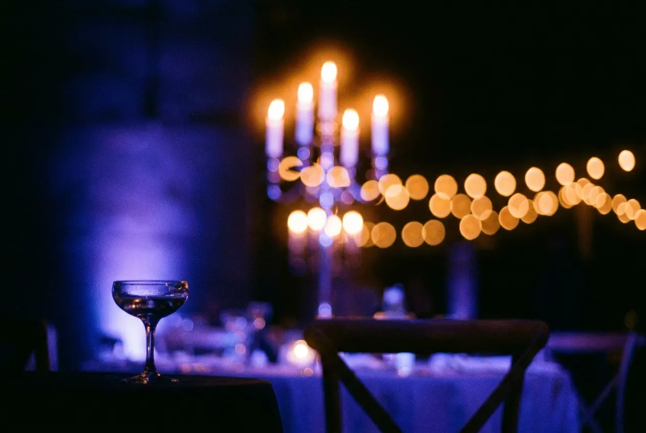 Candlelight and a champagne glass in soft focus on a reception table